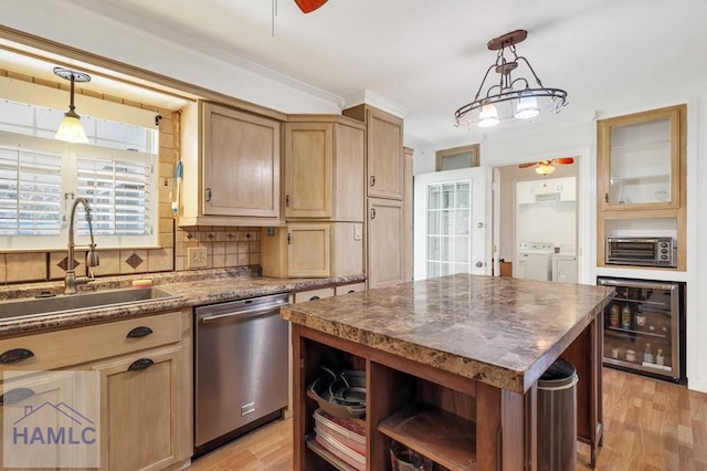 kitchen featuring wine cooler, sink, stainless steel dishwasher, a kitchen island, and washer and clothes dryer