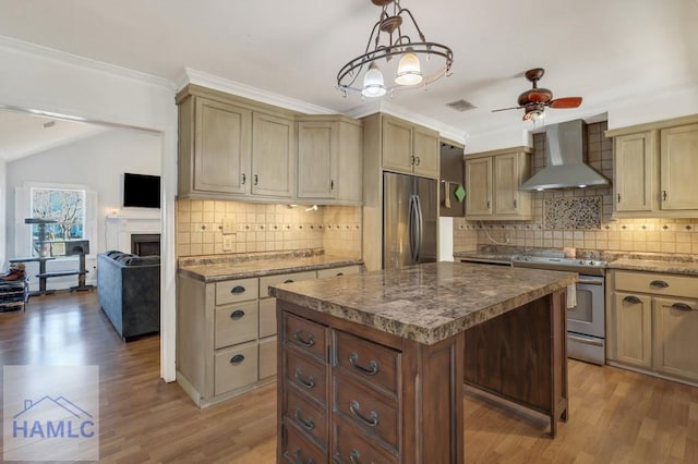 kitchen with pendant lighting, appliances with stainless steel finishes, a center island, wall chimney exhaust hood, and light wood-type flooring