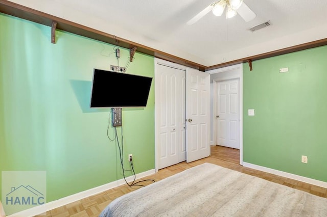 bedroom featuring ceiling fan, light parquet flooring, and a closet