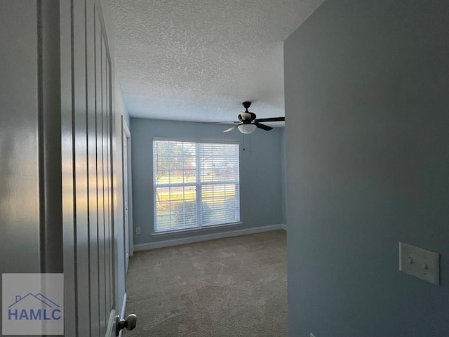 carpeted empty room featuring ceiling fan and a textured ceiling