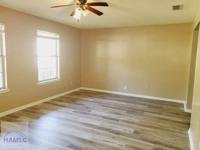 unfurnished room with ceiling fan, hardwood / wood-style floors, and a textured ceiling