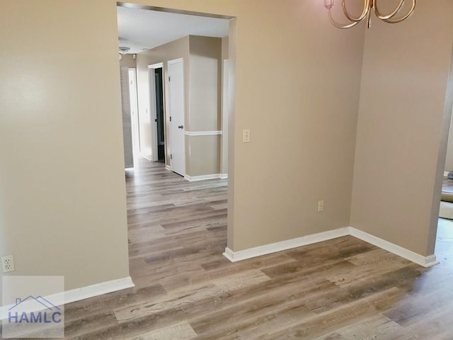 unfurnished dining area with wood-type flooring and a notable chandelier