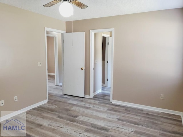 spare room featuring ceiling fan, light wood-type flooring, and a textured ceiling