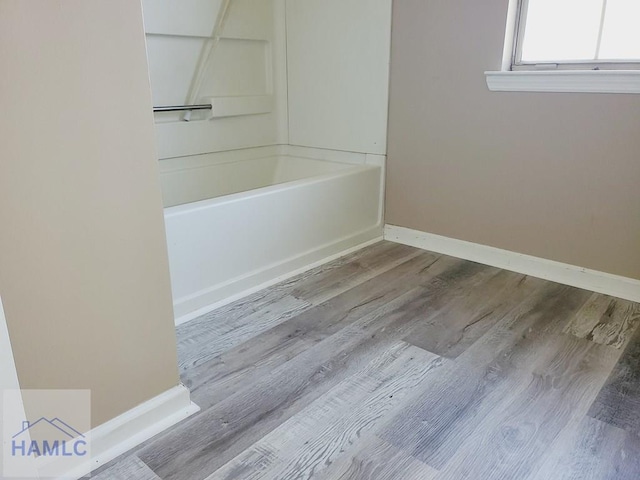 bathroom with wood-type flooring and a tub