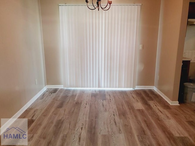 unfurnished dining area with an inviting chandelier and hardwood / wood-style flooring