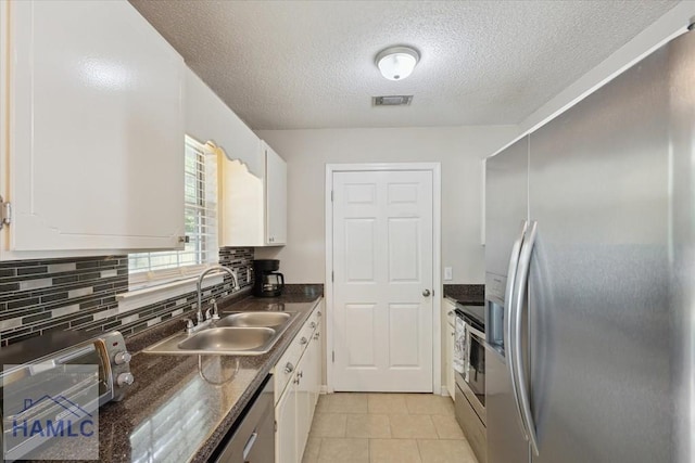128 W Kenny Dr, Hinesville, GA 31313 - kitchen with stainless steel appliances, dark countertops, white cabinets, a textured ceiling, and tasteful backsplash