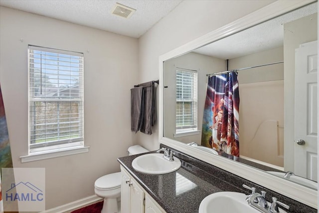 128 W Kenny Dr, Hinesville, GA 31313 - full bathroom with healthy amount of natural light, double vanity, a textured ceiling, and a shower with shower curtain