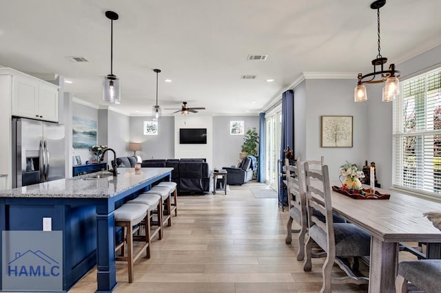 dining room with ceiling fan, light wood-type flooring, visible vents, and ornamental molding