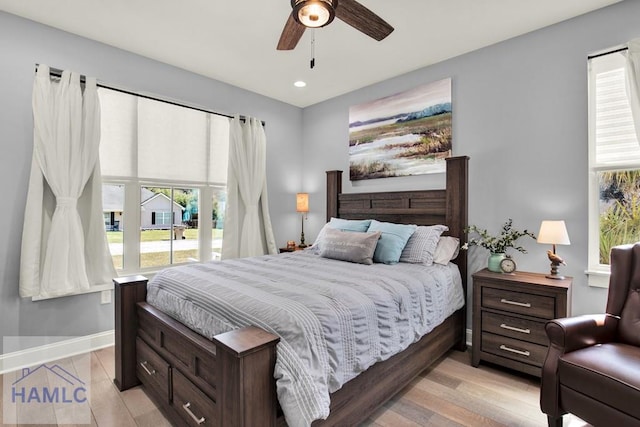 bedroom with light wood-style flooring, a ceiling fan, and baseboards