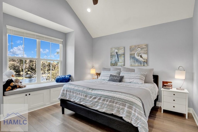 bedroom featuring baseboards, light wood-type flooring, and lofted ceiling