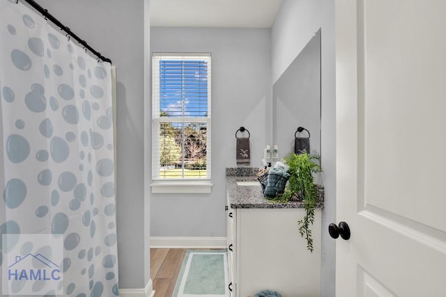 full bathroom featuring a shower with curtain, vanity, baseboards, and wood finished floors