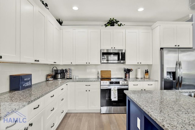 kitchen with light wood-type flooring, light stone counters, tasteful backsplash, stainless steel appliances, and white cabinets