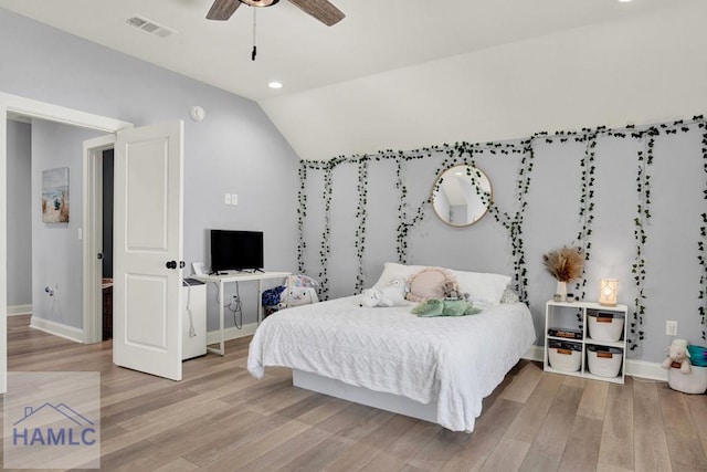 bedroom featuring visible vents, baseboards, light wood-style floors, and vaulted ceiling