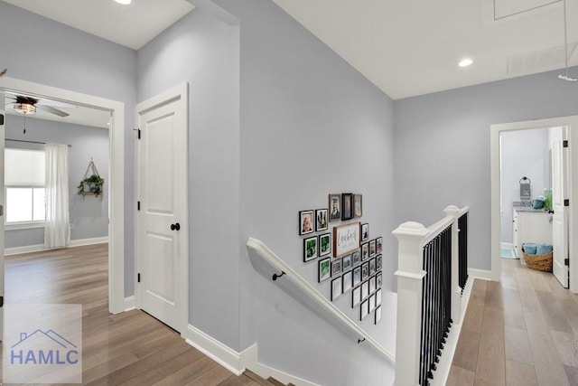 hallway with baseboards, attic access, light wood-type flooring, an upstairs landing, and recessed lighting