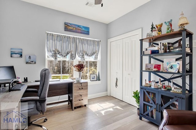 home office featuring a ceiling fan, visible vents, light wood finished floors, and baseboards