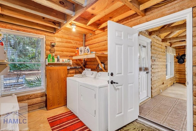 washroom with rustic walls, washer and dryer, and light hardwood / wood-style floors