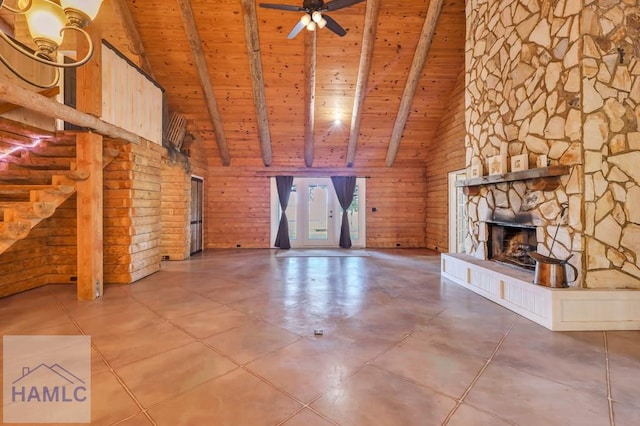 unfurnished living room with ceiling fan, wooden ceiling, beamed ceiling, wood walls, and a fireplace