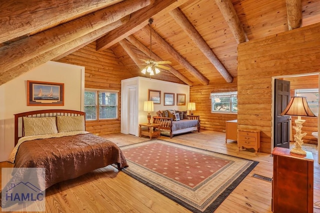 bedroom featuring beamed ceiling, wood-type flooring, multiple windows, and ceiling fan