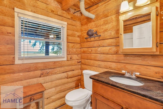 bathroom with vanity, toilet, and log walls