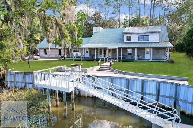 rear view of property with a lawn and a deck with water view