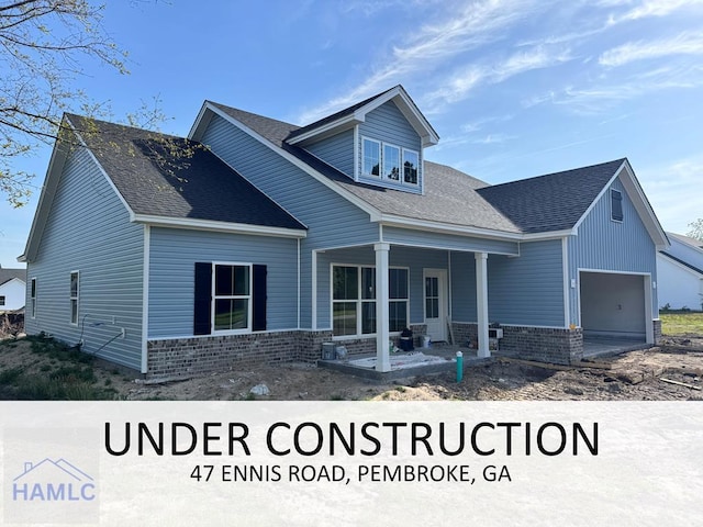47 Ennis Rd, Pembroke, GA 31321 - view of front of home featuring an attached garage, brick siding, a porch, and roof with shingles