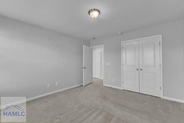 unfurnished bedroom with carpet floors, baseboards, and a closet