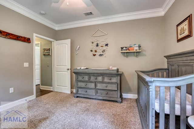 bedroom with ornamental molding, carpet, baseboards, a crib, and ceiling fan