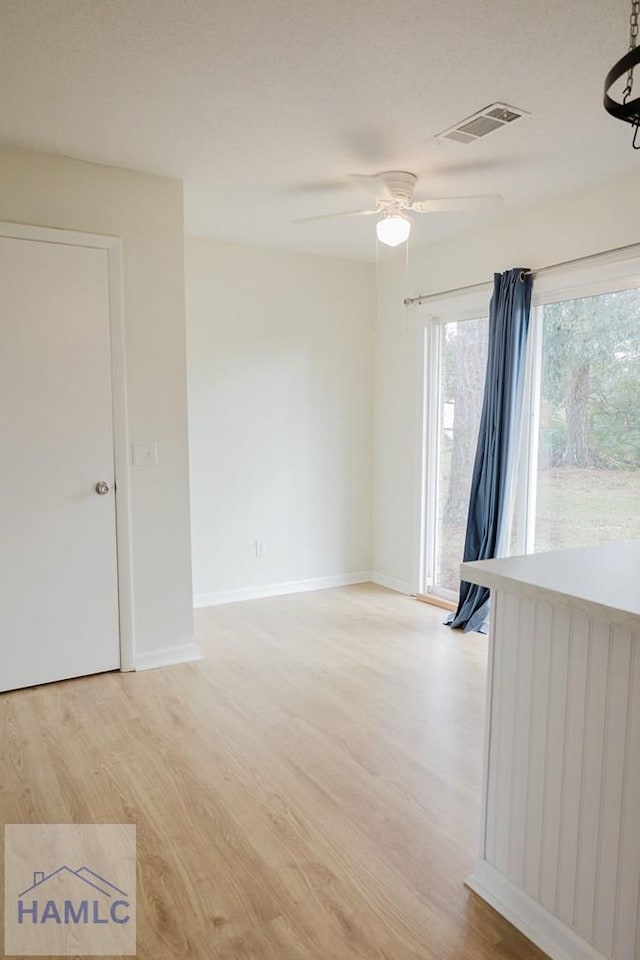 unfurnished room featuring ceiling fan, light hardwood / wood-style floors, and a textured ceiling