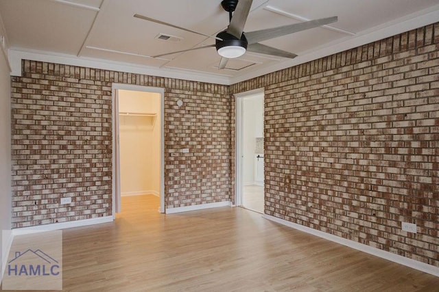 spare room featuring ceiling fan, brick wall, and light wood-type flooring