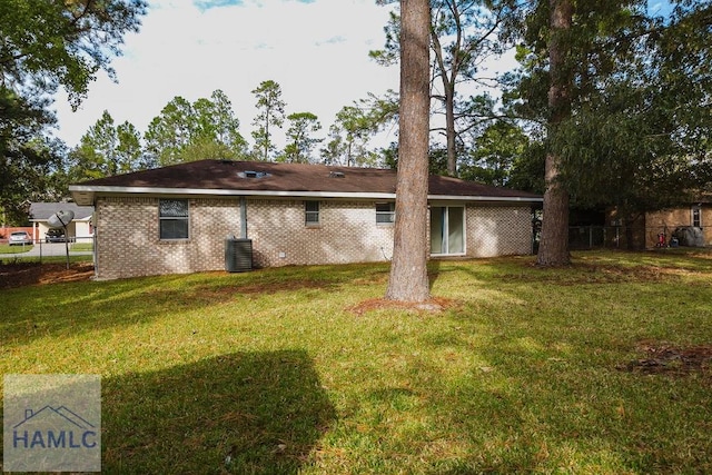 rear view of house featuring central air condition unit and a yard