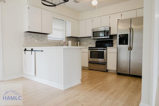 kitchen featuring stainless steel appliances, white cabinetry, tasteful backsplash, and light hardwood / wood-style flooring