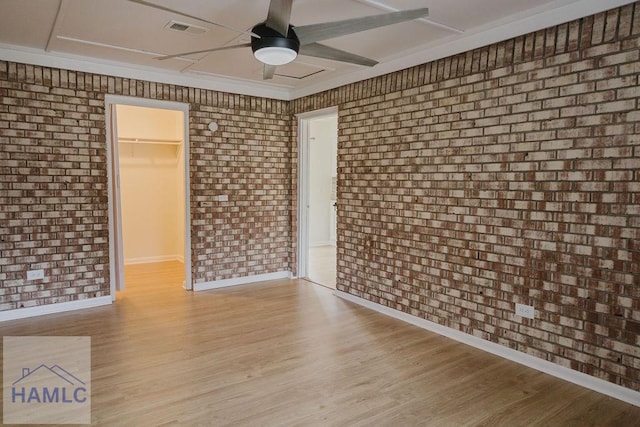 spare room with light wood-type flooring, ceiling fan, and brick wall