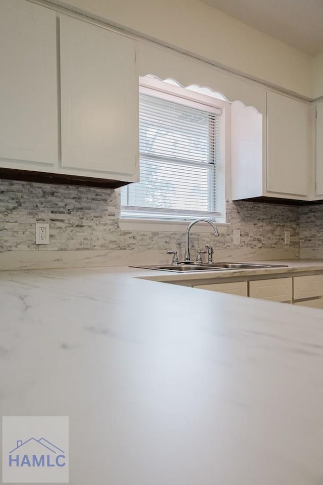 kitchen featuring decorative backsplash, white cabinetry, and sink