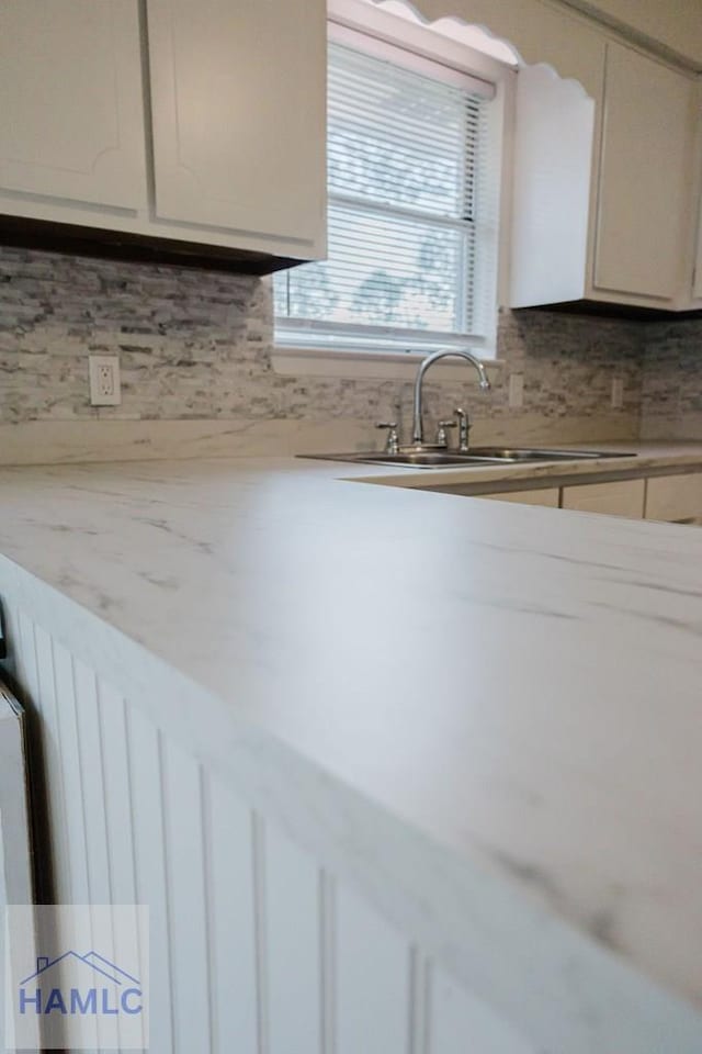 kitchen with white cabinets, decorative backsplash, and sink