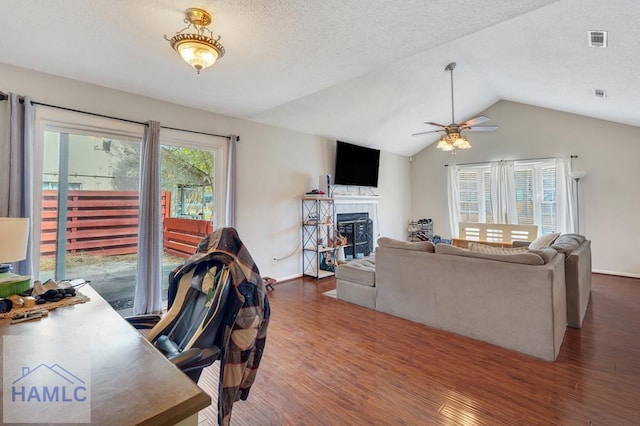 living room with a tile fireplace, lofted ceiling, dark wood-type flooring, and a textured ceiling