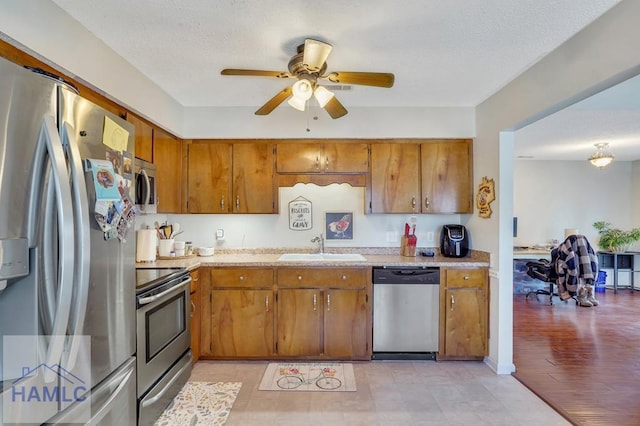 kitchen featuring stainless steel appliances, sink, a textured ceiling, and ceiling fan