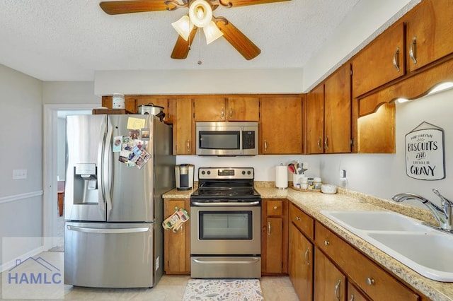 kitchen with ceiling fan, appliances with stainless steel finishes, sink, and a textured ceiling