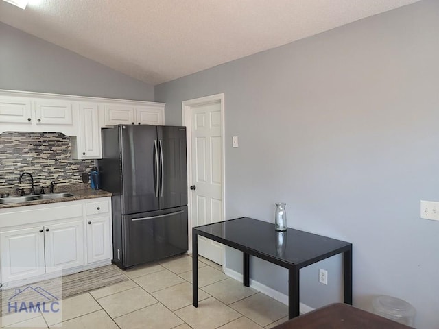 1441 Coalition Cir, Hinesville, GA 31313 - kitchen featuring freestanding refrigerator, decorative backsplash, white cabinets, lofted ceiling, and light tile patterned floors