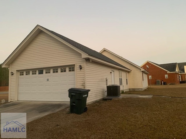 property exterior at dusk featuring central AC unit and a garage