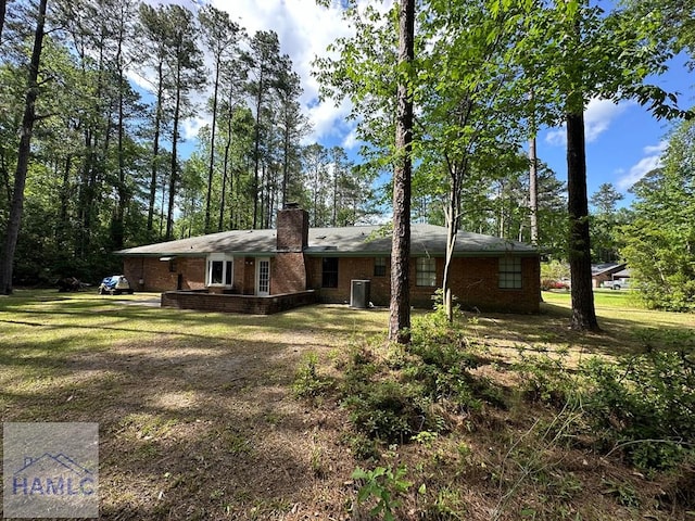 exterior space featuring a chimney, brick siding, and a lawn
