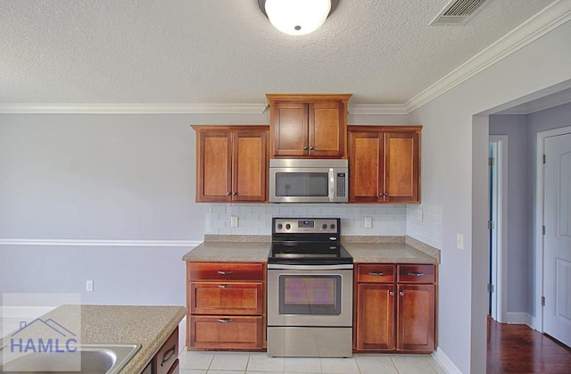 kitchen with backsplash, ornamental molding, a textured ceiling, stainless steel appliances, and light tile patterned floors