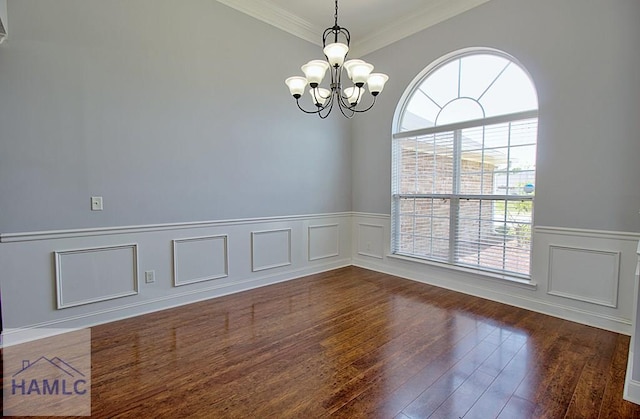 empty room with dark hardwood / wood-style floors, ornamental molding, and a chandelier