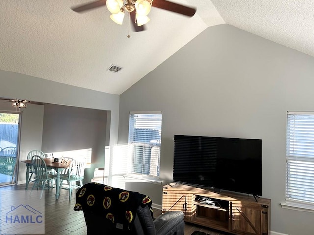 living room with ceiling fan, high vaulted ceiling, wood-type flooring, and a textured ceiling