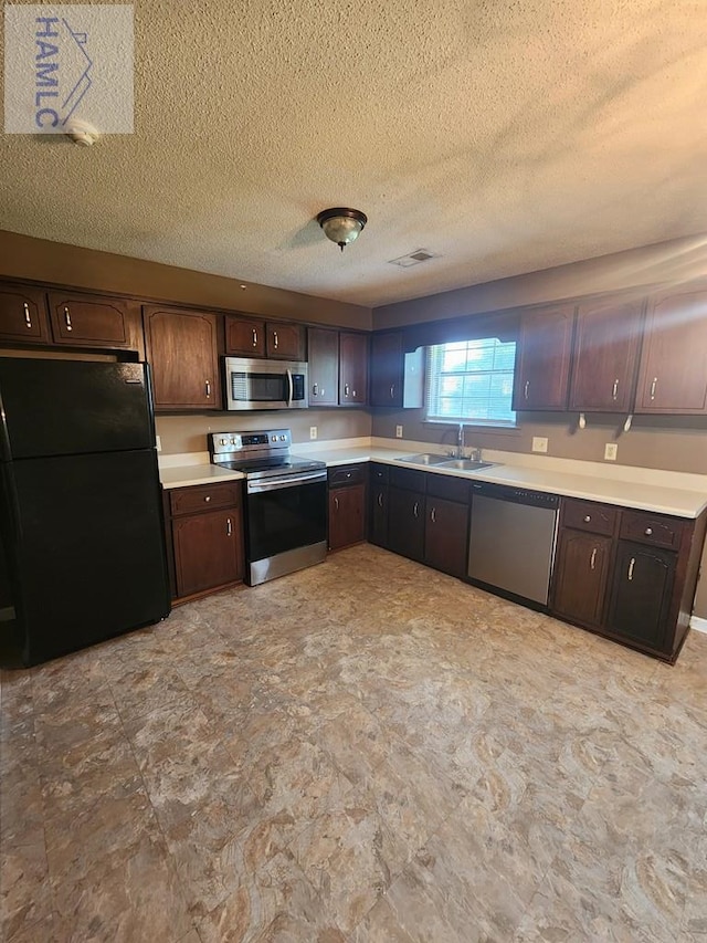 1302 Loblolly Dr, Hinesville, GA 31313 - kitchen featuring stainless steel appliances, light countertops, dark brown cabinetry, a textured ceiling, and stone finish flooring