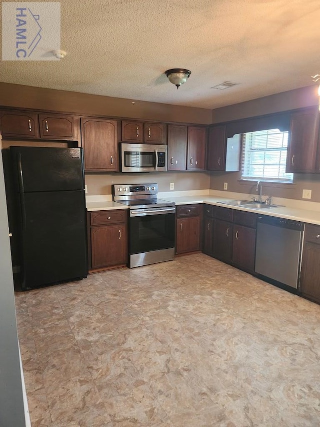 1302 Loblolly Dr, Hinesville, GA 31313 - kitchen featuring appliances with stainless steel finishes, light countertops, dark brown cabinetry, and a textured ceiling