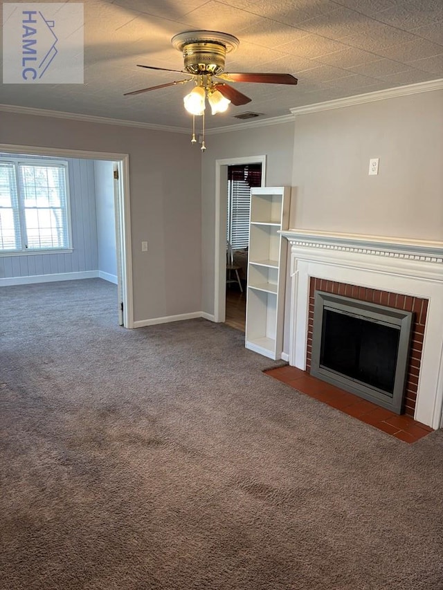 unfurnished living room featuring ceiling fan, a brick fireplace, crown molding, and dark colored carpet