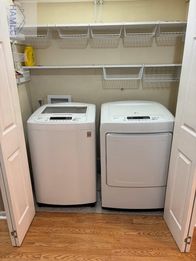 clothes washing area featuring separate washer and dryer and light hardwood / wood-style flooring