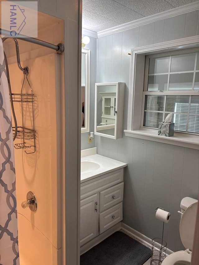 bathroom with a textured ceiling, walk in shower, ornamental molding, and vanity