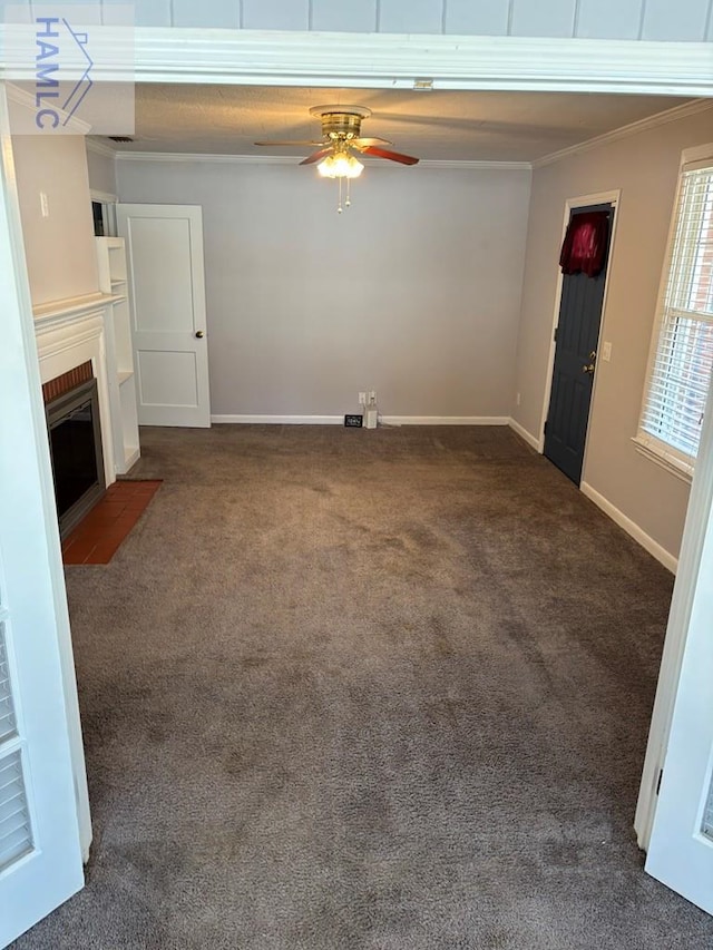 unfurnished living room featuring dark colored carpet, ornamental molding, a fireplace, and ceiling fan