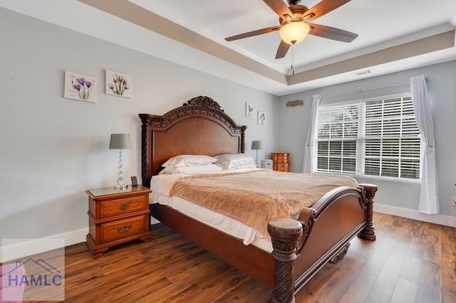 bedroom with ceiling fan, dark hardwood / wood-style floors, a raised ceiling, and crown molding